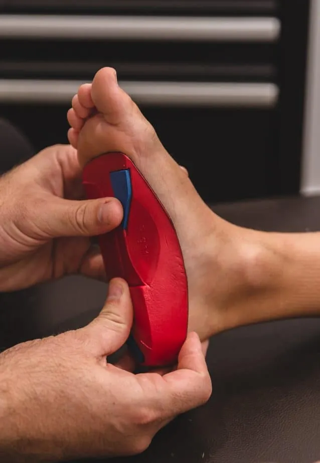 Podiatrist holding a custom orthotic against the sole of a patient's foot