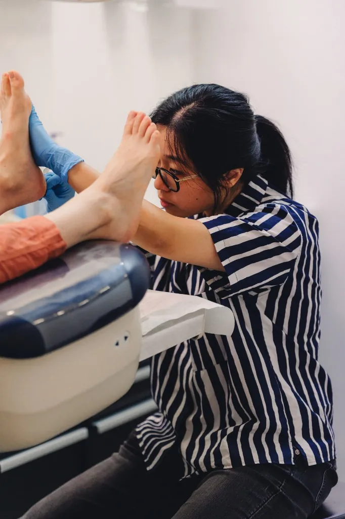 A podiatrist examining a patient's feet on a clinical treatment chair.
